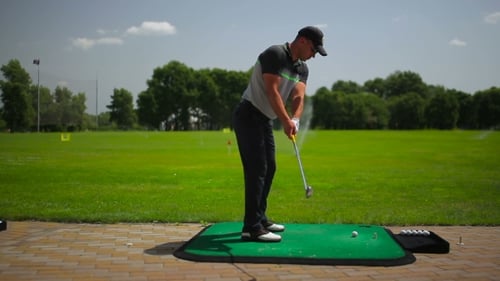 Golfer Swings Club on Sunny Golf Course