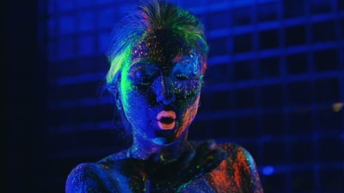 Girl In Ultraviolet Light Blows Pink Fluorescent Powder With Palm