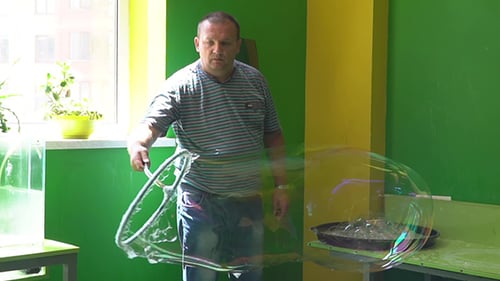 Man Making Giant Bubble Indoors with Wand