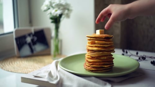 Adding Butter to Stack of Golden Pancakes