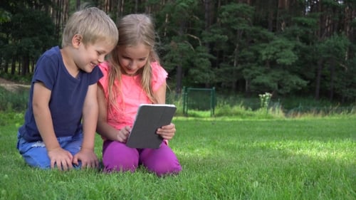Children Using Tablet Device Together on Grass Field