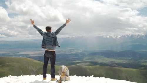 Hiker With Backpack Standing On Top Of a Mountain With Raised Hands And Enjoying Sunrise