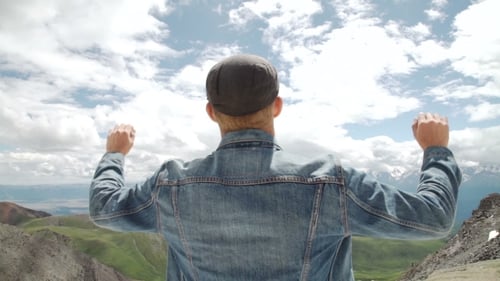 Hiker With Backpack Standing On Top Of a Mountain With Raised Hands And Enjoying Sunrise