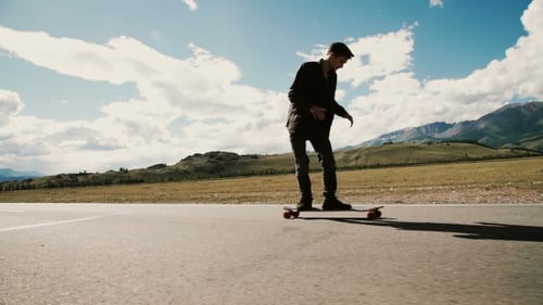 Skateboarder Riding Down Hill At Sunset