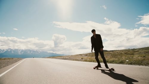 Young Man Skateboarding on Open Mountain Road
