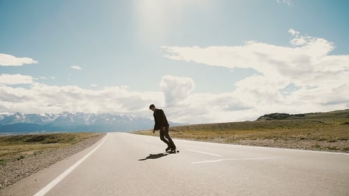 Skateboarder Riding Down Hill At Sunset