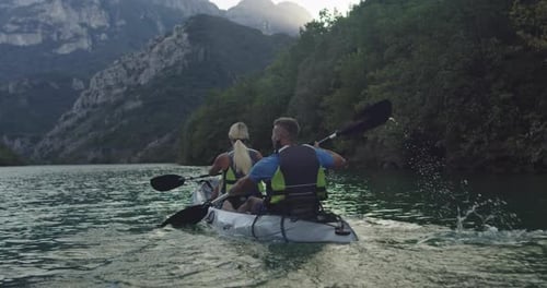 Couple Kayaking on Tranquil Lake Surrounded by Mountains
