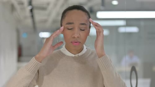 Woman Massaging Temples with Headache in Office