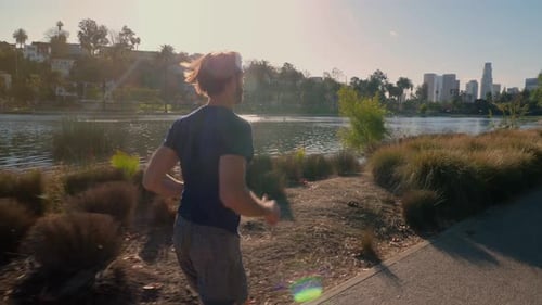 Athletic Man Jogging Around A Small Lake