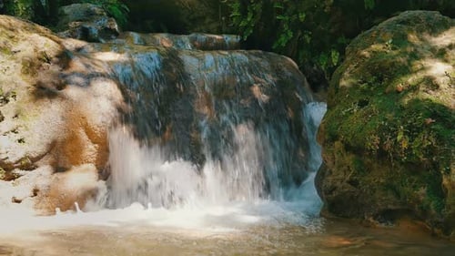 Tropical Waterfall Cascading Over Moss Covered Rocks