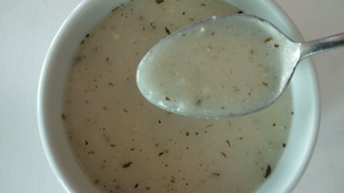 Creamy Soup with Herbs Being Scooped by Spoon