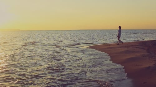 Woman Walking on Golden Beach at Sunset