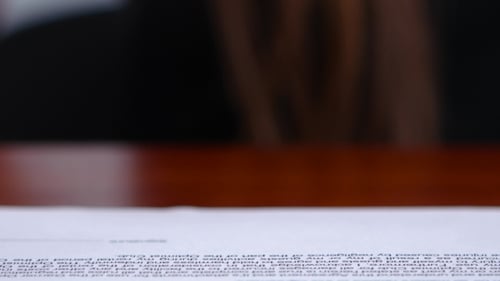El trabajador está haciendo trabajos de oficina en documentos con una impresión rectangular.