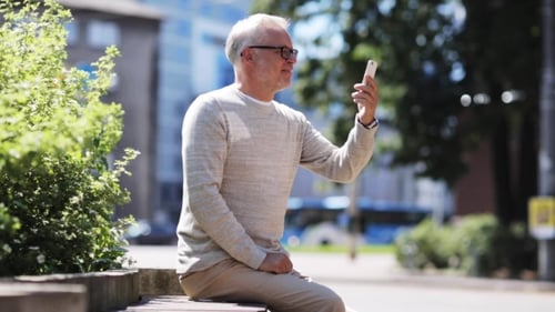 Senior Man Having Video Call On Smartphone In City
