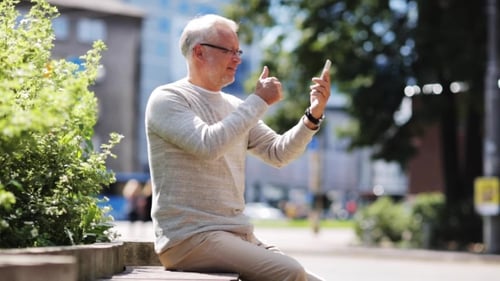 Senior Man Having Video Call On Smartphone In City