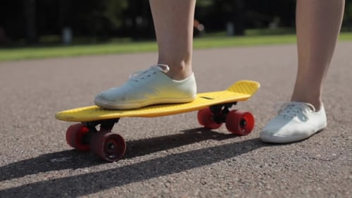 Skateboarder's Feet on Yellow Skateboard in Park