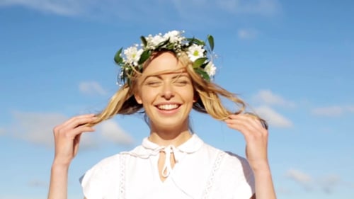 Smiling Woman with Flower Crown Against Blue Sky