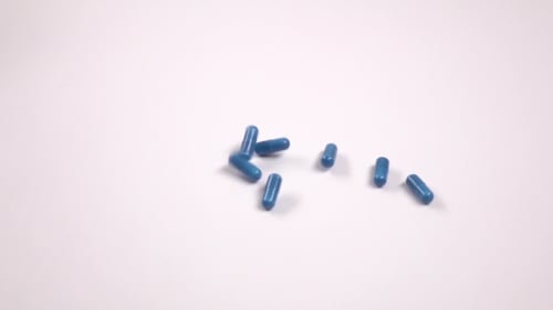 Blue Pills Fall Down on White