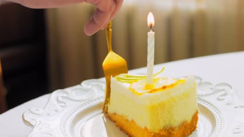 Taking Slice of Birthday Cake with Lit Candle