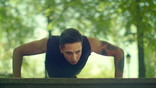 Young Man Doing Push Ups. Athletic Man Making Pushups In Park