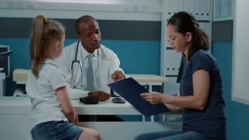 Girl and Mother Consult With Doctor in Clinic