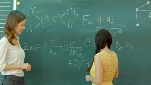 Student schreibt chemisches Symbol auf Tafel