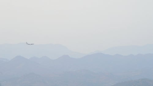Airplane Flies Above Mountain Range