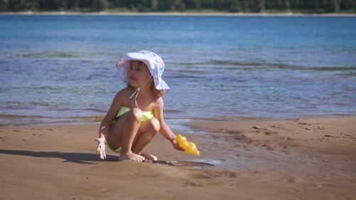 Cute Little Blonde Girl Playing With The Sand At a Lake