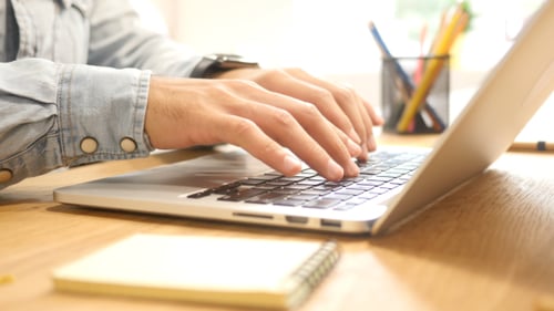 Hands Typing on Laptop in Office Environment