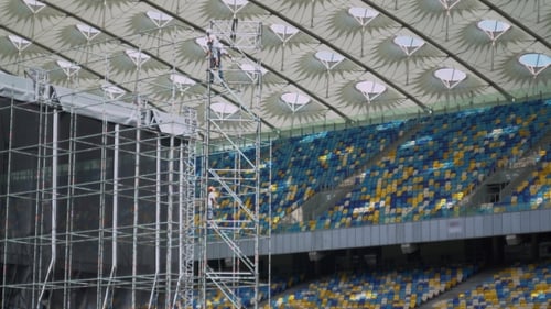 Working Raise Rope Standing In a Construction Ladder On The Big Stadium.