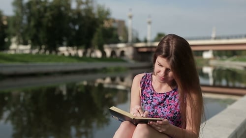 Young Woman Writing in Journal by Urban Canal