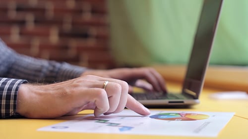 Typing on a Laptop with Business Charts