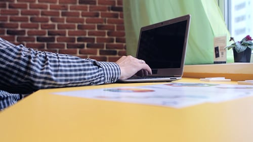 A Man Working On a Laptop And Analyzes The Graph