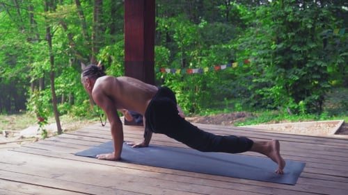 Man Performs Yoga Exercises, Lifting One Leg And Bending The Other.
