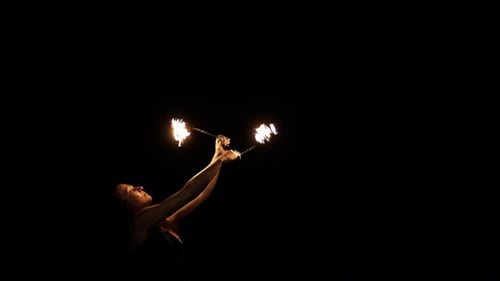 Performer Spins Flaming Torches in the Dark