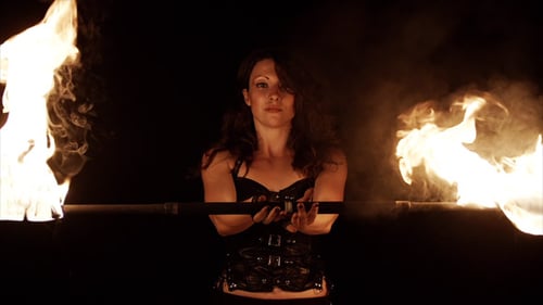 Woman Posing with a Fire Staff in Darkness
