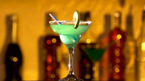 Türkisfarbener Cocktail mit Limetten-Dekor und Kokosnuss am Rand