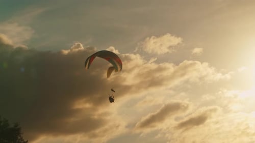 Zwei Gleitschirmflieger schweben in einem wunderschönen goldenen Himmel gegen den Sonnenuntergang