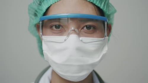 Nahaufnahme eines asiatischen Arztes oder einer Krankenschwester mit Gesichtsmaske in medizinischer Schutzuniform.
