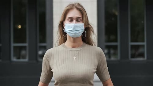 Woman wearing a mask in front of a building