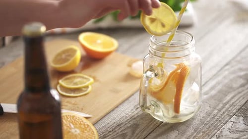 Preparing A Summer Refreshing Drink With Lemon And Orange Wedges. Glass On The Table With Slices