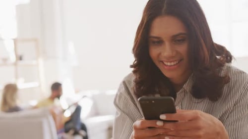 Woman Using Smartphone with Friends Playing Guitar Indoors