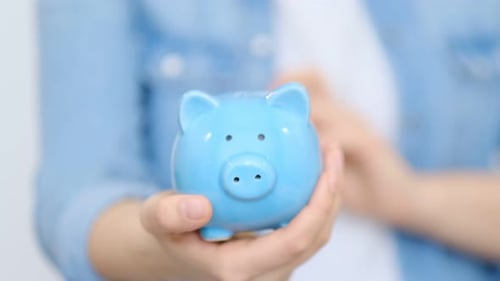 Putting Money into Blue Piggy Bank for Savings