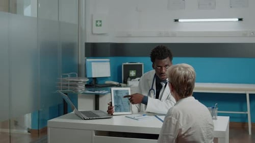 Junger Physiotherapeut zeigt Tablette mit Knochenverletzung