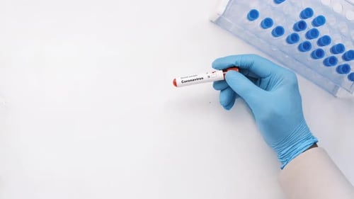 Gloved Hand Holding Coronavirus Test Tube