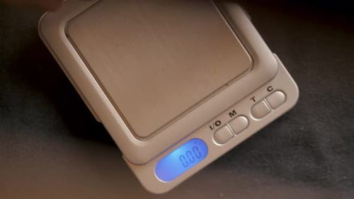 Close Up of Hand Placing Matter on Scale