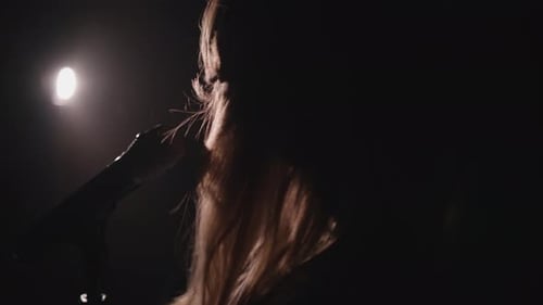 Close-up of the Face of the Singer with Microphone on a Black Smoky Background. The Singer Sings a
