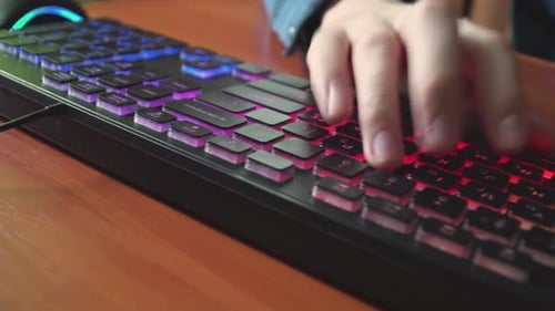 A Man Types Text on a Backlit Keyboard