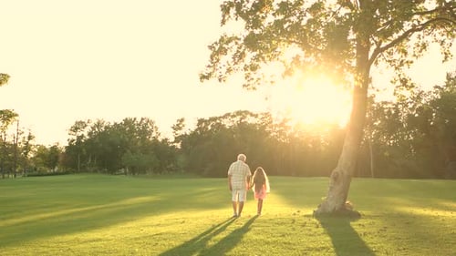 Grandfather and Granddaughter Walk at Sunset
