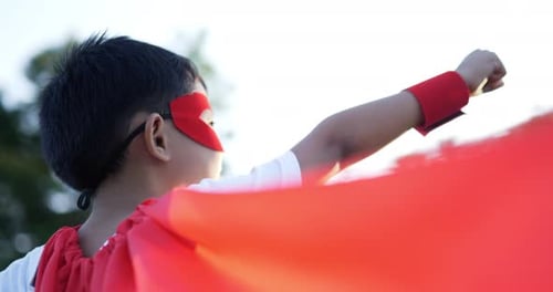 Back of Super hero kid flying outdoor against park